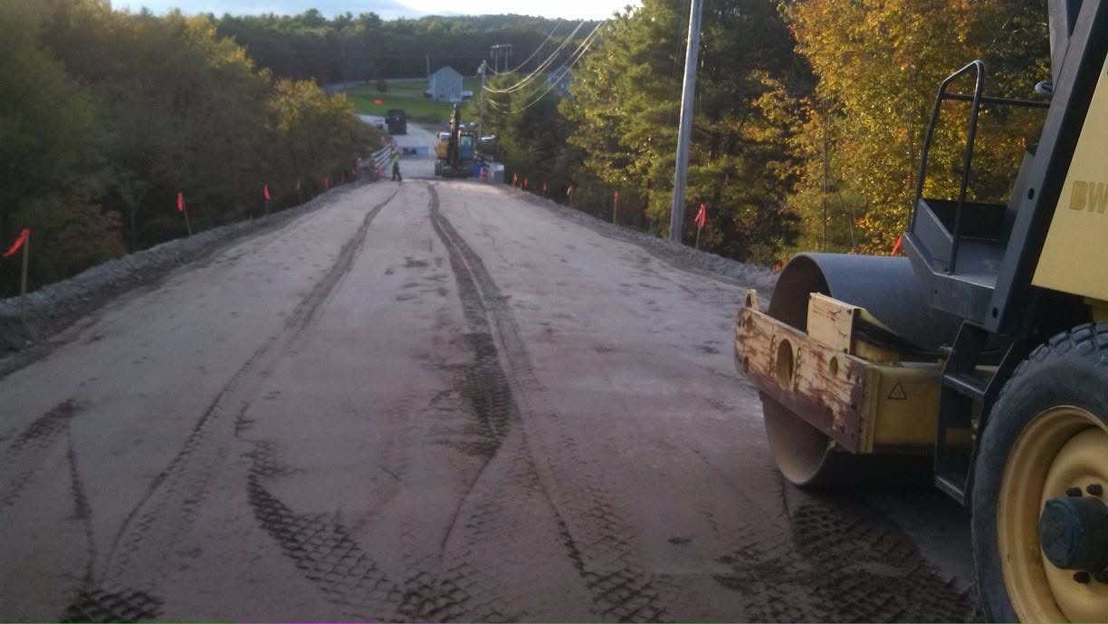 Bridge approach embankment lifts being placed and compacted with a smooth drum roller