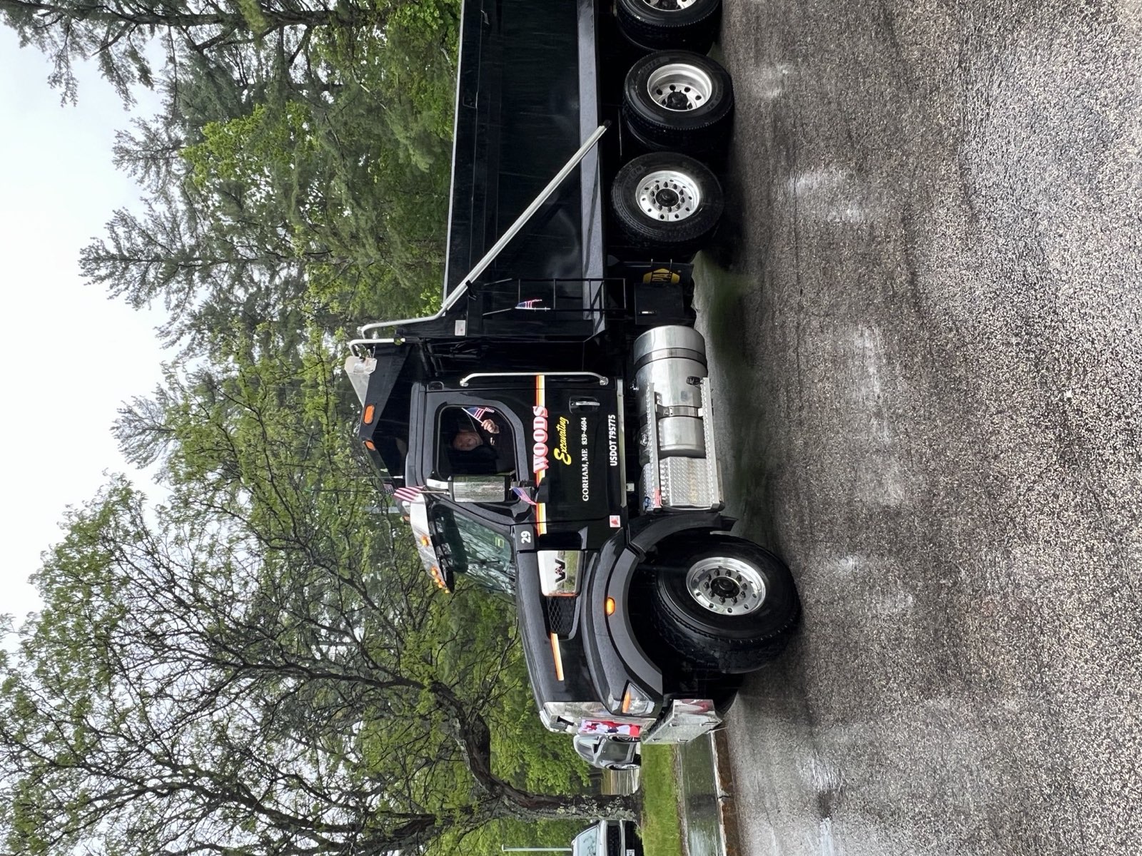 Woods driver leaning out the cab with a flag, the lettered door and parade bunting on the grille
