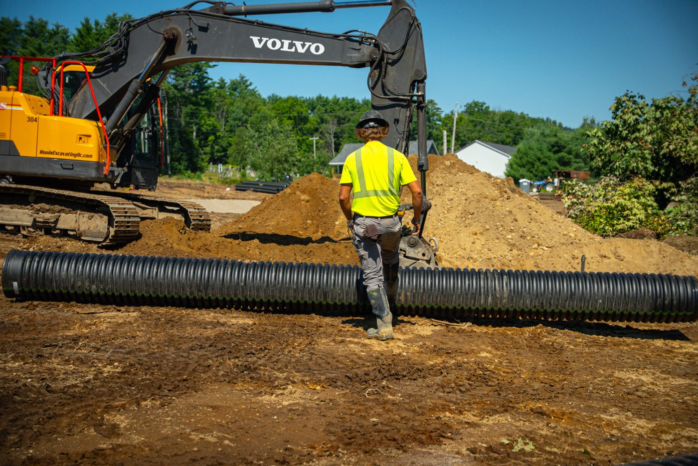 A Woods crew member working the culvert pipe run ahead of the excavator