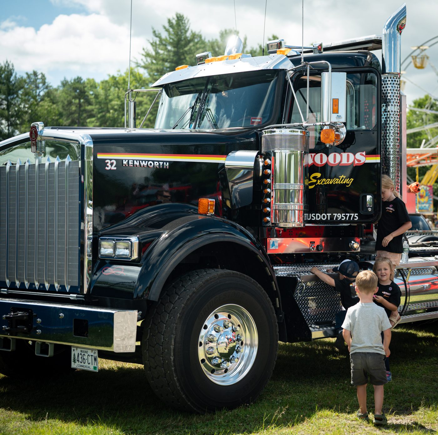 The Woods Excavating show truck, the name on the door, a small child at the bumper